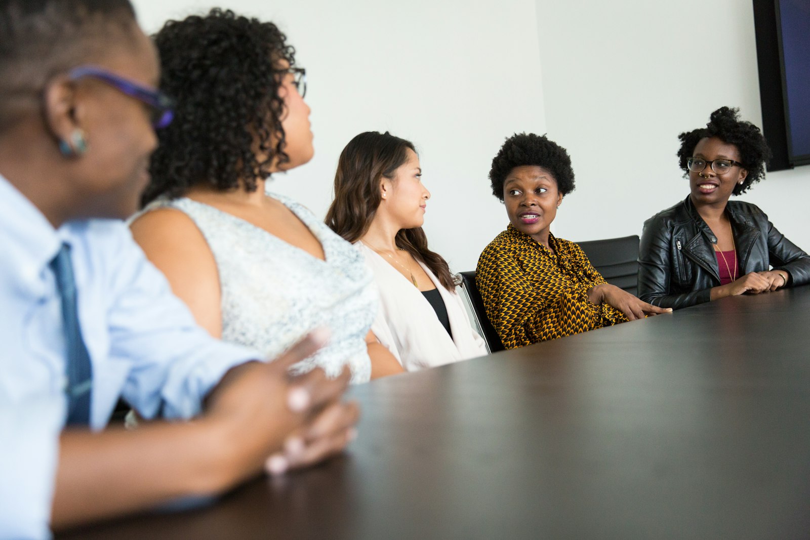 A diverse group of women engaged in a respectful, attentive conversation around a shared table